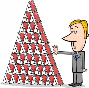 Man pulling a card out of a house of cards